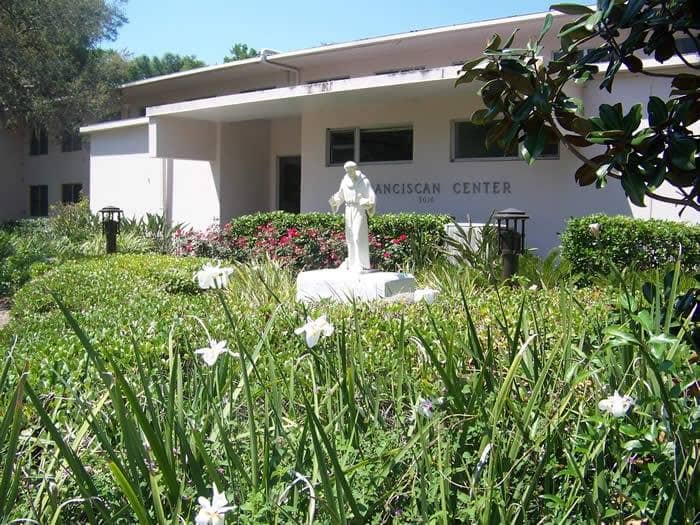 Front of the building with statue in the yard